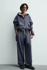 Pantalón jogger de corte wide fit confeccionado en algodón con interior de rizo. Presenta cintura elástica ajustable con cordón, bolsillos laterales y un bolsillo trasero de plastrón. Cuenta con un efecto lavado y acabados irregulares en el ruedo.