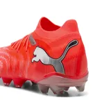 Championes de fútbol Puma Future Match FG/AG, color naranja vibrante con detalles en plateado. Presentan un diseño de caña media tejida y suela con tapones mixtos para césped natural y artificial.