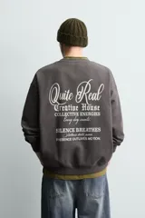Sudadera gris oscuro de corte relaxed fit, cuello redondo y manga larga, con estampa en contraste en el pecho y acabados en rib.