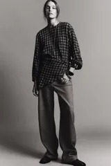 Camisa de manga larga con estampado a cuadros en blanco y negro. Presenta un cuello redondo y un pañuelo multiposición que cae en un drapeado asimétrico sobre el frente.