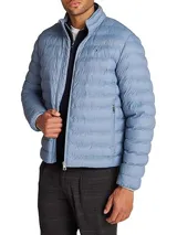 Campera acolchada Tommy Hilfiger color celeste, repelente al agua, con cuello alto, cierre de cremallera, dos bolsillos laterales con cremallera, logo de Tommy Hilfiger bordado en el pecho y diseño plegable.