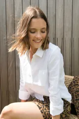 Camisa blanca de lino, de corte clásico, con cuello camisero, manga larga y bolsillo en el pecho.