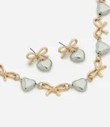 Conjunto de bijouterie compuesto por un collar corto y un par de aros a juego. El diseño presenta dijes alternados de lazos dorados y corazones plateados. El collar cuenta con cadena de eslabones y cierre de mosquetón con extensor, mientras que los aros son de tipo colgante con base de lazo y dije de corazón.