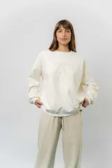 Buzo oversize de algodón frizado color crema, con cuello redondo, puños y cintura tejidos. Presenta un bordado tono sobre tono de Garfield en el centro del frente.