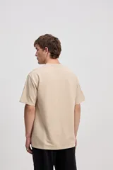 Remera de manga corta color beige con tejido texturado y pequeño logo impreso en el pecho.