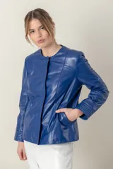 Campera azul de cuero ovino italiano, con cuello redondo, cierre frontal con broches ocultos, bolsillos laterales y detalle de capitoneado en puños y bolsillos.