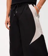 Pantalón barrel de poliéster color negro con recortes contrastantes en tono gris claro en los laterales, de corte amplio y urbano con cintura elástica.