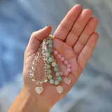 Set de tres pulseras elásticas con piedras naturales: una de cuarzo cristal, una de amazonita y una de cuarzo rosa. Cada pulsera cuenta con un dije colgante en forma de corazón de cuarzo con detalles en baño de oro.