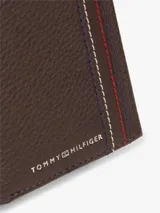 Billetera plegable de piel granulada Tommy Hilfiger, color marrón, con diseño en tres partes, costuras decorativas tricolor en el frente y logo metálico de la marca.