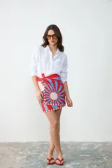 Pareo rectangular estampado con diseño geométrico radial en tonos rojo, celeste y blanco, inspirado en la arquitectura Art Decó. Confeccionado en Uruguay, ideal para usar como falda cruzada, accesorio de playa o chal.