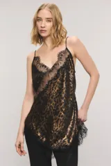 Top de satén con estampado animal print tipo leopardo y detalles de encaje negro en el escote y el ruedo asimétrico. Cuenta con breteles finos regulables y escote en V.