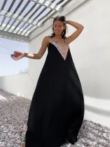 Vestido largo de fiesta color negro, con corte holgado y escote en V profundo decorado con lentejuelas doradas.