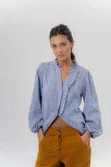 Camisa de manga larga color beige con diseño a rayas sutiles, cuello mao con volados y abertura frontal con detalles de volados a un lado.