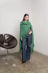 Poncho tejido color verde con cuello alto y flecos largos.