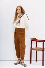 Pantalon cargo color marrón, de calce relajado con ajuste elástico en los tobillos. Presenta bolsillos laterales con solapa y cintura con cierre, botón y elástico en la parte posterior.