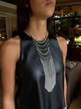 Collar de diseño llamativo compuesto por múltiples capas de cadenas doradas y barras metálicas verticales que descienden en un fleco largo y fluido.