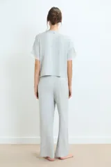 Pijama de dos piezas en color gris melange, compuesto por una remera de manga corta con detalles de encaje en los bordes y un pantalón de corte recto con cintura elástica y detalle de encaje en la pretina.