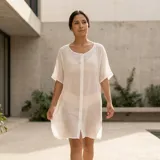 Camisa holgada blanca de manga corta y largo medio, confeccionada en mezcla de algodón, con cierre frontal de botones.