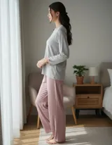 Pijama de dos piezas compuesto por una remera de manga larga gris con cuello redondo y botones frontales, y un pantalón largo de corte recto en color rosado.