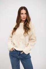 Buzo de tejido de punto con diseño floral en tonos crema y beige, de corte holgado, cuello redondo y mangas largas con puños acanalados.