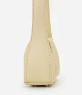 Cartera tipo baguette marca Satinato, confeccionada en PU color beige, con diseño estructurado, detalles fruncidos laterales y asa fija para el hombro.