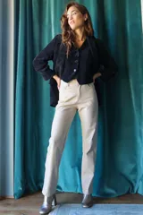 Pantalón de cuerina color beige, de corte recto y tiro alto, con detalle de costuras verticales en el frente.