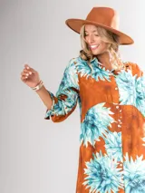 Vestido camisero largo con estampado floral en tonos rojos y negros, con cuello camisero, abotonadura frontal y mangas largas con puños abotonados.