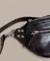 Riñonera de cuero color negro, con múltiples compartimentos con cierre metálico, detalles de tachas en los laterales y correa regulable.