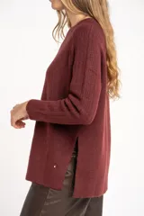 Sweater de punto con textura acanalada, cuello redondo y mangas largas. Presenta un diseño de calce holgado con ruedo redondeado y aberturas laterales.