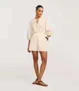 Short de cintura alta color crema, con bolsillos laterales y bordados abstractos en los costados.