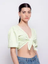 Top estampado con flores rosas, hojas verdes y líneas negras, de manga corta abullonada con nudo en el escote.