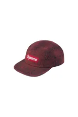 Gorra tipo camp cap de Supreme, confeccionada en denim con estampado de letras estilo Old English en relieve, color rojo oscuro y negro, con el icónico logo box logo de la marca en el frente.