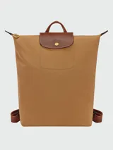 Mochila de diseño minimalista en color beige, con solapa y asa superior en cuero marrón texturizado. Cuenta con correas ajustables en color marrón y cierre principal.