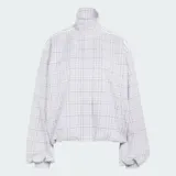 Campera Adidas de corte oversize y mangas voluminosas, con cuello alto, cierre frontal y diseño a cuadros en color gris.