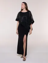 Vestido largo azul marino de seda fría, compuesto por una falda recta con tajo frontal y una capa superior superpuesta de encaje con lentejuelas bordadas, escote a la base y mangas tres cuartos acampanadas.