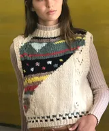 Chaleco de punto artesanal confeccionado en 100% lana merino, con diseño frontal multicolor de patrones geométricos en diagonal sobre base cruda, cuello redondo y terminaciones acanaladas.