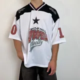 Camiseta blanca de estilo deportivo con cuello en V y mangas cortas. Presenta detalles en negro en los hombros y cuello, y un estampado con una estrella y la inscripción "Power Velocity". Tiene números en las mangas.