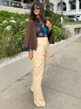 Pantalón de vestir color beige, de corte recto y tiro alto, con pinzas frontales y cintura ancha.