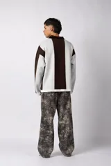 Sweater de tejido de punto con diseño de rayas verticales en tonos beige y blanco. Presenta cuello polo abierto, mangas largas y un corte holgado. Incluye un logo bordado en el centro del pecho.