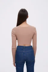 Top color beige de tejido de punto acanalado, con mangas largas y abertura en el pecho.