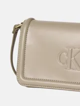 Cartera bandolera Calvin Klein de piel sintética suave en color beige, con solapa, cierre magnético, correa ajustable y monograma CK en relieve en la parte delantera.