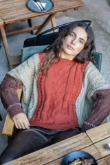 Sweater de punto con diseño de ochos y estilo patchwork, combinando paneles en colores terracota, marrón y beige. Presenta cuello redondo, mangas largas y costuras decorativas a la vista.