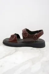 Sandalias marrones de cuero con suela de goma negra y ajuste con velcro.