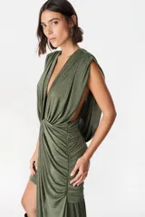 Vestido corto de diseño asimétrico en color verde oliva, con escote profundo en V, drapeado frontal y una caída lateral larga que llega hasta el suelo. Sin mangas y con ajuste entallado en la falda.
