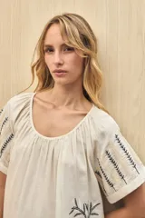 Vestido corto color crudo con bordado de hojas en el ruedo y en las mangas.