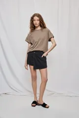 Falda short de denim con diseño a rayas verticales y costuras en contraste. Presenta frente asimétrico con efecto de falda, tiro medio, bolsillos delanteros y cierre con botón.
