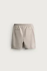 Bermuda regular fit de tejido elástico color blanco, con cintura elástica ajustable mediante cordón, bolsillos delanteros y bolsillos traseros de vivo.