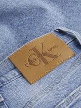 Pantalón de jean celeste de corte mom, tiro alto, cinco bolsillos y cierre con cremallera.