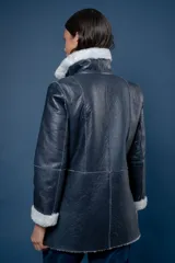 Campera reversible de cuero ovino, color azul marino, con interior de piel sintética blanca. Presenta cuello alto, cierre frontal y bolsillos frontales aplicados.