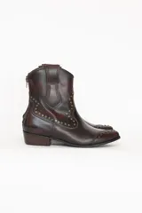 Bota texana de caña baja marca Brava, confeccionada en cuero color marrón tinto con efecto envejecido. Cuenta con taco bajo, puntera fina y detalles de tachas metálicas aplicadas en los laterales y la puntera.